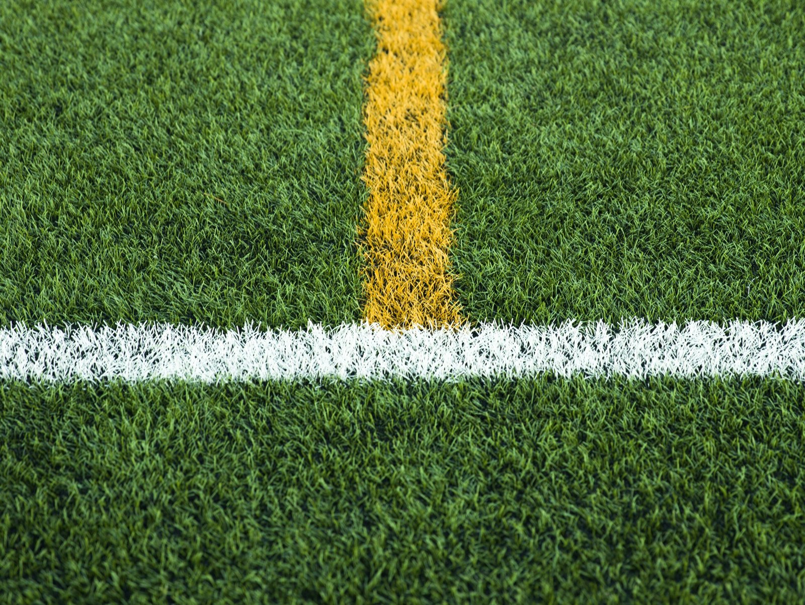 Green artificial grass turf soccer football field with white and yellow line boundary